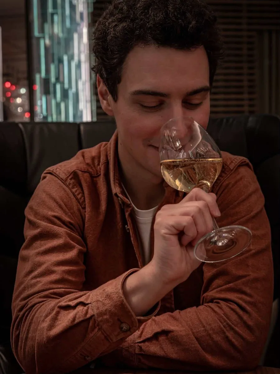Alexis Attimont, un verre de champagne à la main, dans une lumière chaude